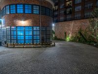 some dark blue windows in an industrial building with no one on the street to the right