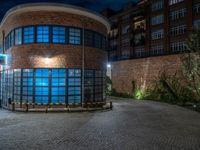 some dark blue windows in an industrial building with no one on the street to the right