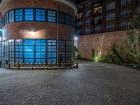 some dark blue windows in an industrial building with no one on the street to the right