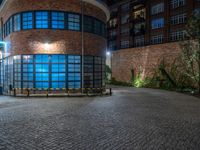 some dark blue windows in an industrial building with no one on the street to the right