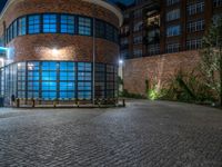 some dark blue windows in an industrial building with no one on the street to the right