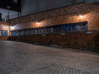 some dark blue windows in an industrial building with no one on the street to the right