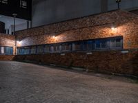 some dark blue windows in an industrial building with no one on the street to the right