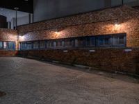 some dark blue windows in an industrial building with no one on the street to the right