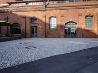 an empty courtyard with brick buildings next to a metal door and street light that reads ebbem