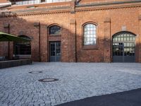 an empty courtyard with brick buildings next to a metal door and street light that reads ebbem