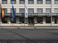 a bus is on the street next to many flags in front of a building on the road