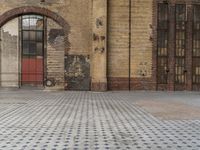 a parking sign is on the ground of a cobblestone sidewalk in front of an industrial building