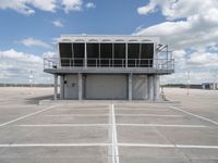 a large parking garage sitting next to an airport hangar type building on an empty runway