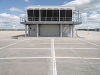 a large parking garage sitting next to an airport hangar type building on an empty runway