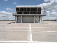 a large parking garage sitting next to an airport hangar type building on an empty runway