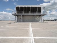 a large parking garage sitting next to an airport hangar type building on an empty runway