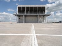 a large parking garage sitting next to an airport hangar type building on an empty runway