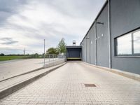 a blue building with metal fenced parking spaces and doors on one side and a parking lot on the other