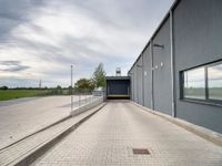 a blue building with metal fenced parking spaces and doors on one side and a parking lot on the other