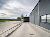 a blue building with metal fenced parking spaces and doors on one side and a parking lot on the other