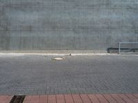 an empty bench sitting next to a large concrete building behind it with red bricks on either side