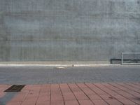 an empty bench sitting next to a large concrete building behind it with red bricks on either side