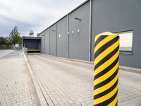 an image of a yellow and black stripe posts next to a building entrance entrance is visible