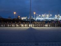 an empty parking lot under cloudy skies in the evening with lots of lights on it