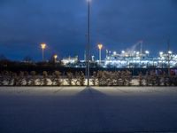 an empty parking lot under cloudy skies in the evening with lots of lights on it