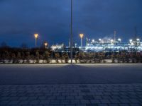 an empty parking lot under cloudy skies in the evening with lots of lights on it