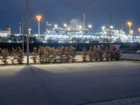 a night scene with an oil refinery in the distance with some trees around it and lights