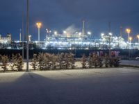 a night scene with an oil refinery in the distance with some trees around it and lights