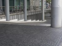 a bike rack on a walkway near some buildings and people walking down the street from them