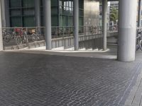 a bike rack on a walkway near some buildings and people walking down the street from them