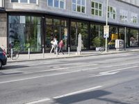 a woman that is walking by a building with a bike on it and people on the sidewalk