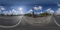 a wide angle view of an intersection with clouds in the sky behind it and a bridge on one side