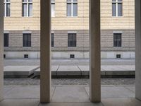 columns and a concrete path are shown in front of several buildings in this image, it looks very open