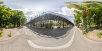 a fish eye lens view of a pedestrian bridge over a street in a park on a nice day