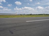 an empty road with some white clouds in the sky near the air traffic control tower