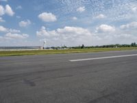 an empty road with some white clouds in the sky near the air traffic control tower