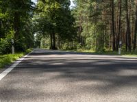 an empty road with the trees to the side of it and some green grass on the other side