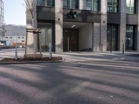 a traffic light sits in front of an office building on a street corner, with two streets