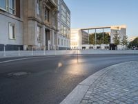 an empty street in front of a big building near the city street is surrounded by barbed wire