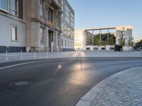 an empty street in front of a big building near the city street is surrounded by barbed wire