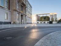 an empty street in front of a big building near the city street is surrounded by barbed wire