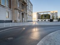 an empty street in front of a big building near the city street is surrounded by barbed wire