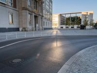 an empty street in front of a big building near the city street is surrounded by barbed wire