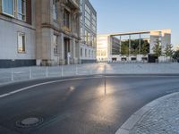 an empty street in front of a big building near the city street is surrounded by barbed wire