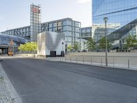 some tall buildings a road and a person on a skateboard in the street and one person walking next to the sidewalk