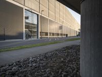 a sidewalk in front of a building with a bunch of rocks on it and an empty street