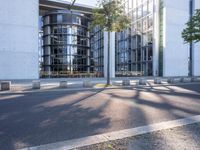 the modern building has an entrance and glass facade, along with bench seating, trees, and a street with lots of windows