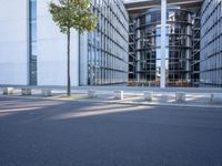 the modern building has an entrance and glass facade, along with bench seating, trees, and a street with lots of windows