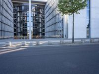 the modern building has an entrance and glass facade, along with bench seating, trees, and a street with lots of windows