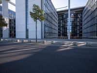 the modern building has an entrance and glass facade, along with bench seating, trees, and a street with lots of windows